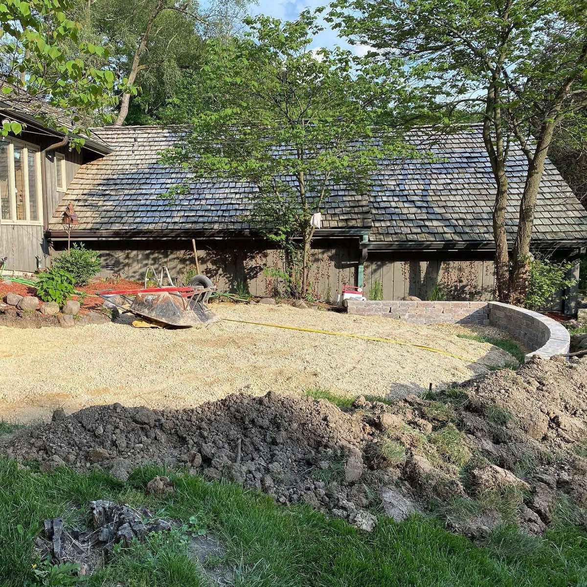 Excavated yard with compacted gravel base and retaining wall started
