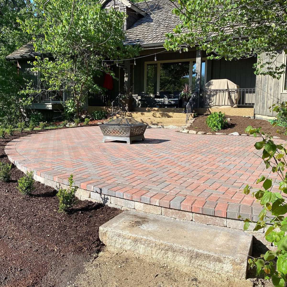 Finished circular paver patio with fire pit and mulched planting beds