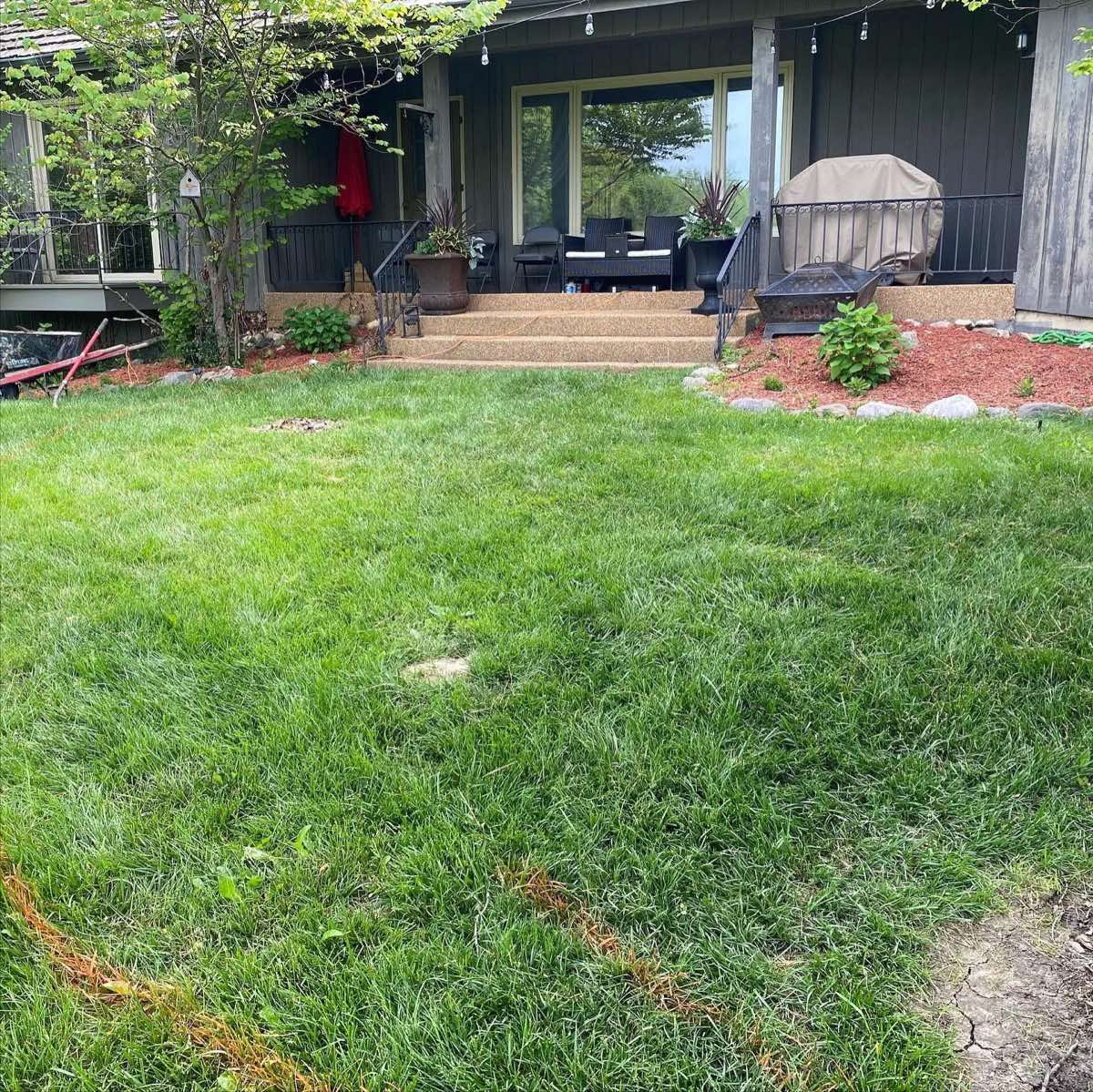 Plain sloped back lawn in front of porch before patio construction