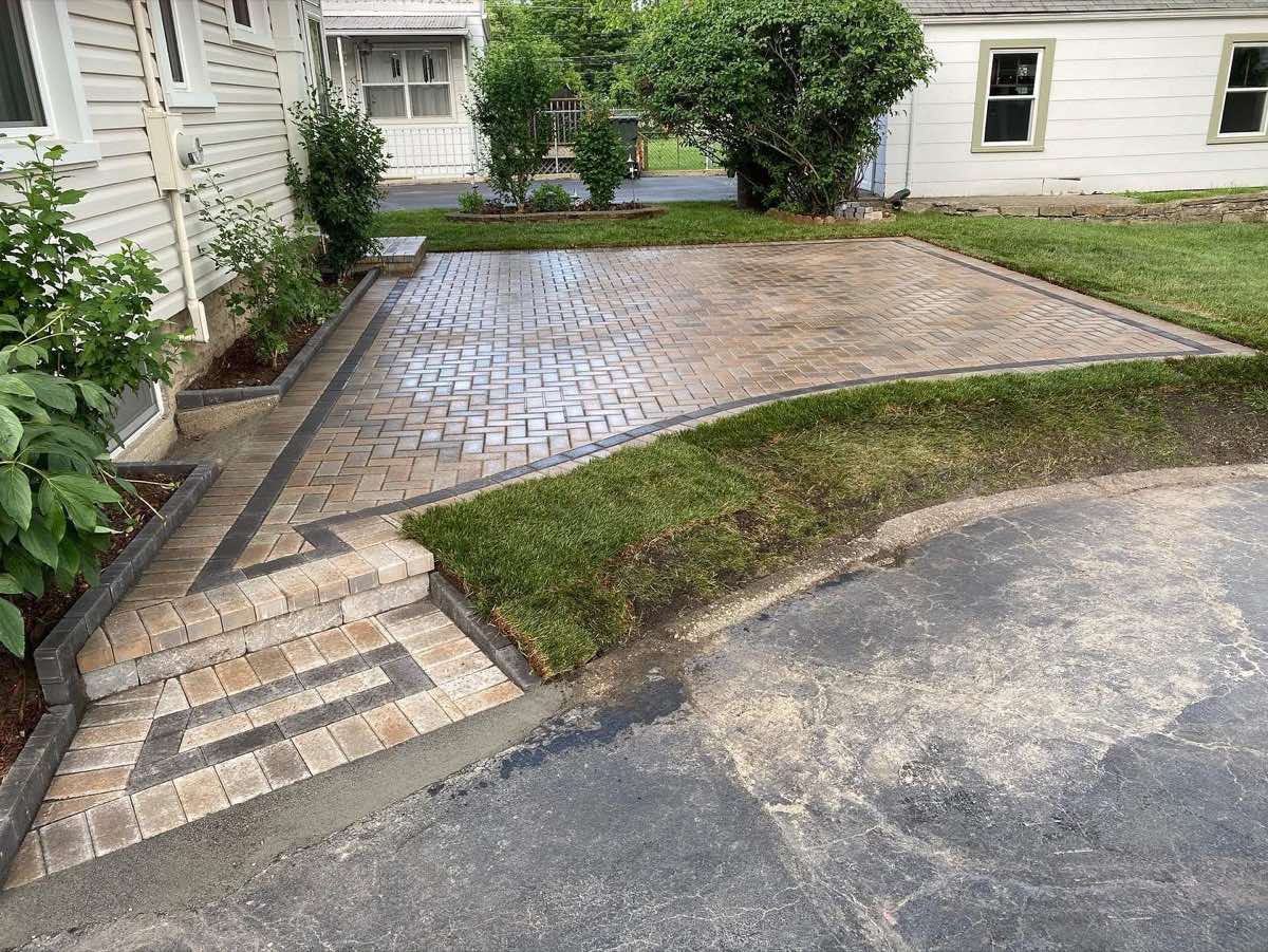 Custom paver steps with geometric inlay and fresh sod at patio edge